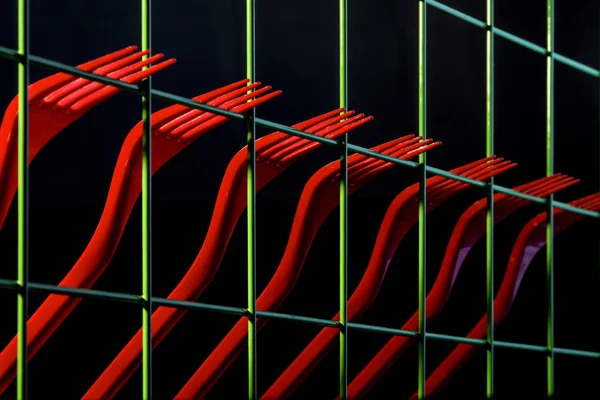 Abstract still life with red forks and green fence against a dark background