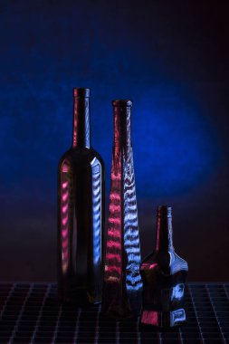 Karanlık bir arka planda üç cam şişe ile sakin bir hayat