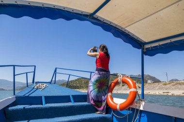 Skadar Gölü, Karadağ - 02 Ağustos 2017: Bir kadın Skadar Gölü'nü bir zevk teknesinin kenarından fotoğrafla