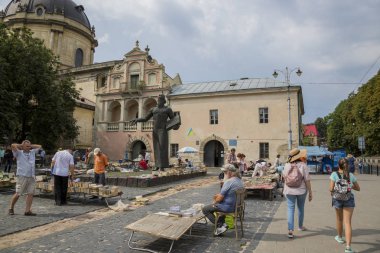 Lviv, Ukrayna - 13 Ağustos 2019: Podvalnaya Caddesi'ndeki Lviv'de Ivan Fedorov anıtının önündeki kitap pazarındaki insanlar