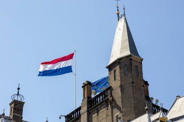 Gökyüzüne karşı bir binanın çatısında Hollanda ve Avrupa Birliği bayrakları