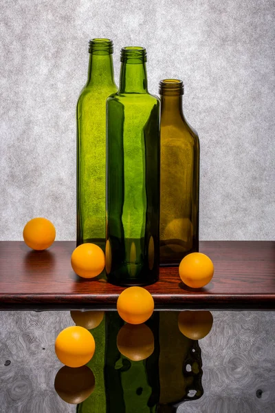 Natureza Morta Com Garrafas Coloridas Bolas Laranja Uma Superfície Reflexiva — Fotografia de Stock