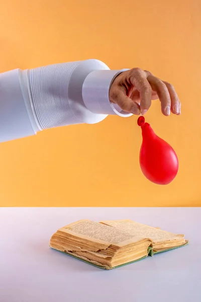 Människans Hand Med Deflaterad Ballong Över Bok — Stockfoto