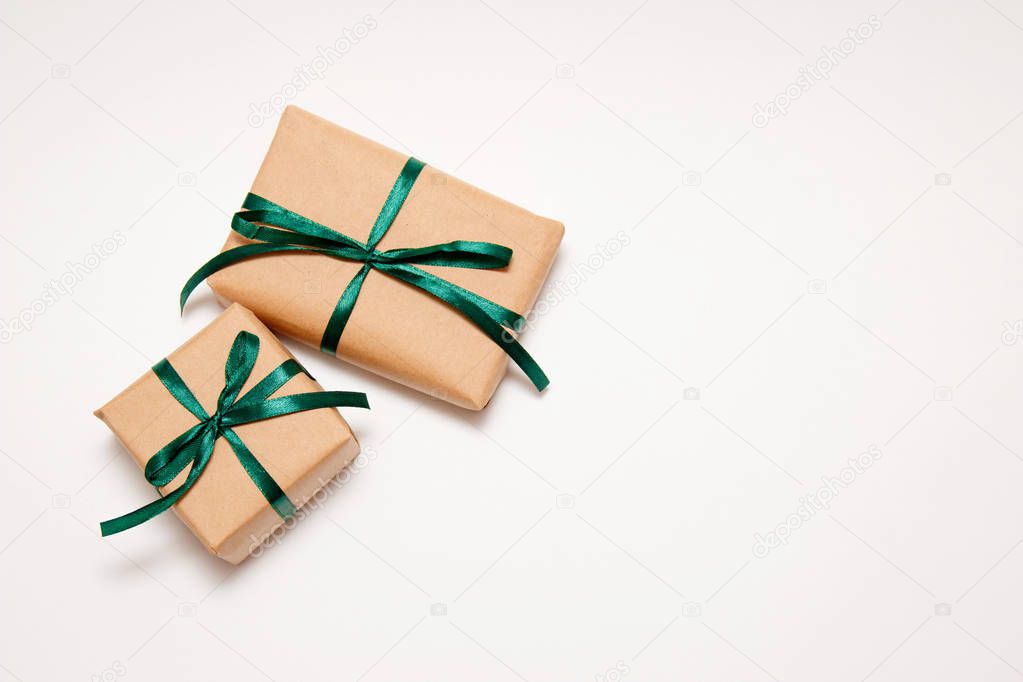 Closeup two gifts from craft paper with a green ribbon on a white background. Horizontal format. Sale concept