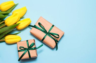 Bir buket Sarı laleler ve mavi kağıt arka plan üzerinde iki tekne hediye. Pring arka plan, anneler günü ya da Sevgililer günü tebrik kartı, kopya alanı, düz yatıyordu