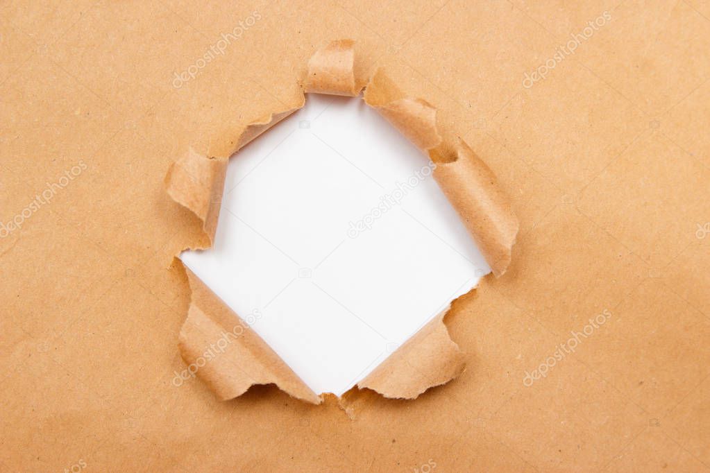 Hole into brown craft paper sheet with torn edges. White center isolated, clipping path included. Top view.