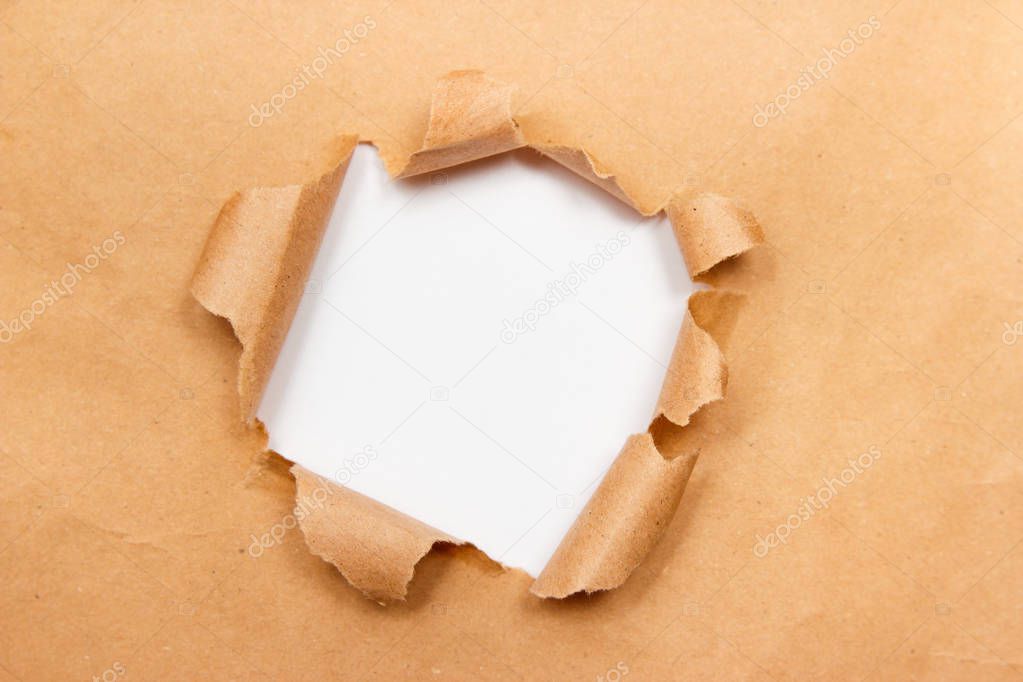 Hole into brown craft paper sheet with torn edges. White center isolated, clipping path included. Top view.