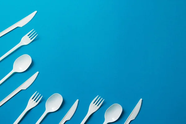 Plastic Forks, Spoons and Knives on Blue Background