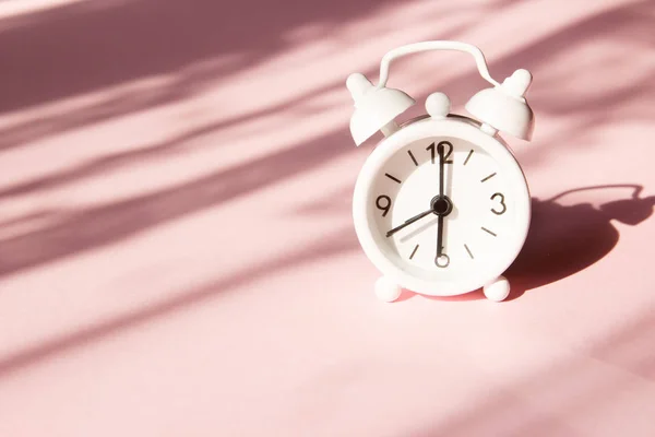 ピンクの背景に目覚まし時計。朝の時間の背景の概念 — ストック写真