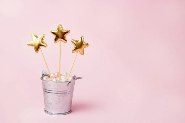 Drie glanzende sterren in een ijzeren decoratieve emmer op een roze achtergrond. Decoraties voor vakantie feest. Ruimte kopiëren — Stockfoto