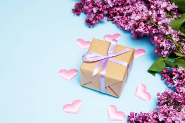 Mavi bir arka plan üzerinde hediye kutusu ile leylak çiçekler çerçeve. Üst te. Anneler günü