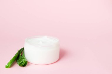 Pembe bir arka plan üzerinde krem ve aloe vera kavanoz. Kopyalama alanı