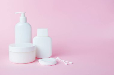White jars of cosmetics on a pink background. Bath accessories. Face and body care concept
