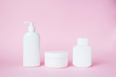 White jars of cosmetics on a pink background. Bath accessories. Face and body care concept