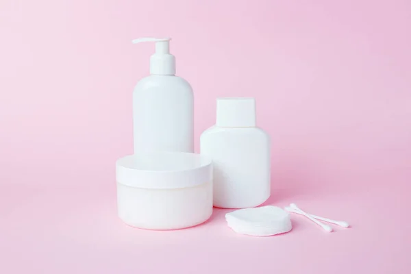 White jars of cosmetics on a pink background. Bath accessories. Face and body care concept