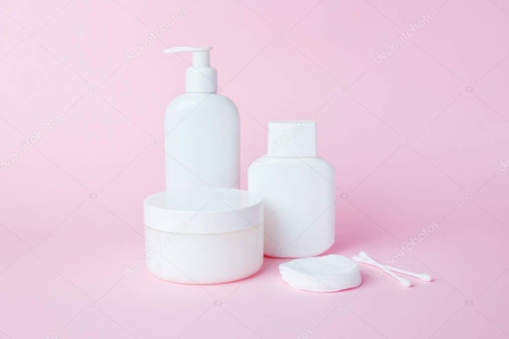 White jars of cosmetics on a pink background. Bath accessories. Face and body care concept