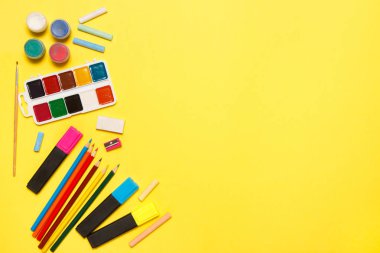 Eğitim ve okul kavramına geri dönelim. Sarı bir arka plan üzerine çizim için okul malzemeleri. Üst görünüm, düz yatıyordu.