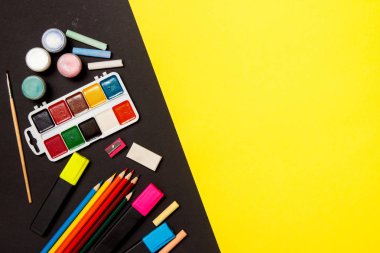 Eğitim ve okul kavramına geri dönelim. Sarı bir arka plan üzerine çizim için okul malzemeleri. Üst görünüm, düz yatıyordu.
