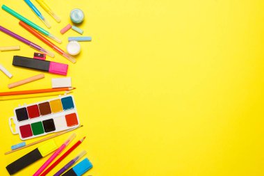 Eğitim ve okul kavramına geri dönelim. Sarı bir arka plan üzerine çizim için okul malzemeleri. Üst görünüm, düz yatıyordu