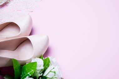 Düğün ayakkabıları ve buket pembe arka plan üzerinde yatıyor. Yakından kapatın. düz yatıyordu. üst görünüm.