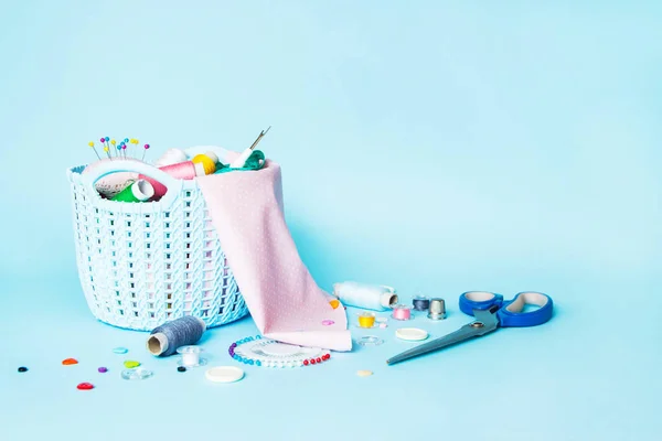 Basket with sewing supplies on a blue background. Copy space. Dressmaker and designer desk