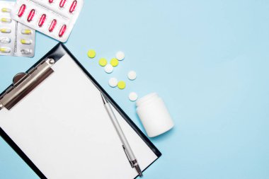 Doktor reçete yazmak için boş kağıt üst görünümü. Mavi arka planda haplar