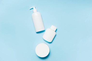 Mavi arka planda beyaz kozmetik kavanozları. Banyo aksesuarları. Yüz ve vücut bakım konsepti