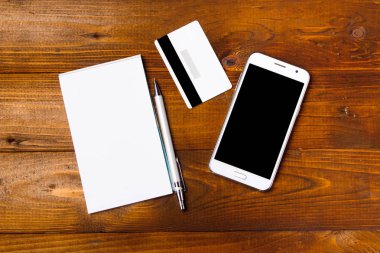 Ahşap masa üzerinde akıllı telefon ve dizüstü bilgisayar ile kredi kartı. Yukarıdan görüntüle.