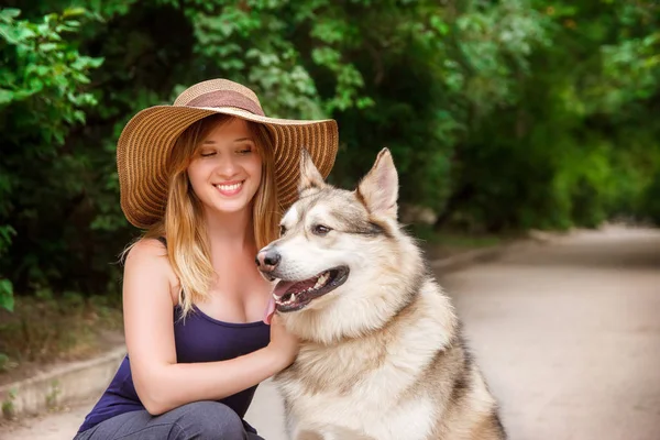 Happy young woman hugs siberian husky in the park. The concept of care and walking with a dog