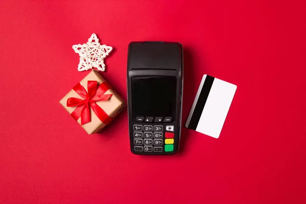 Terminal de pago con tarjeta de crédito y regalo sobre fondo rojo. concepto de venta de Navidad . —  Fotos de Stock