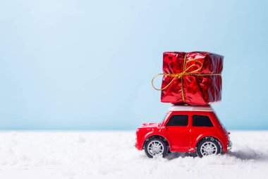 Mavi arka plan üzerinde hediye kutusu teslim Minyatür kırmızı araba oyuncak. Noel tebrik kartı kavramı.