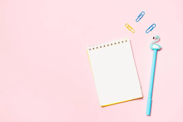 Kladblok met gekleurde pen en paperclips op een roze achtergrond. School-en werkruimte concept. Platte lay, bovenaanzicht — Stockfoto