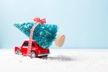 Ukrayna, Kuiv - 16 Ağustos 2019: Minyatür kırmızı araba oyuncak mavi arka plan üzerinde noel ağacı teslim. Noel tebrik kartı kavramı.
