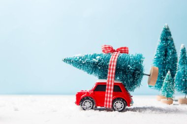 Ukrayna, Kuiv - 16 Ağustos 2019: Minyatür kırmızı araba oyuncak mavi arka plan üzerinde noel ağacı teslim. Noel tebrik kartı konsepti. Yakın çekim