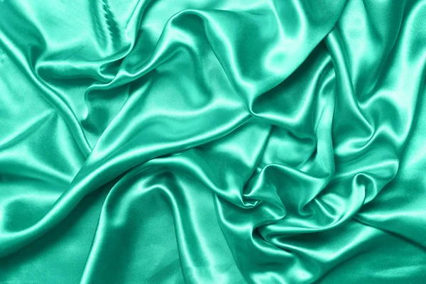 Крупним планом брижі на шовковій тканині. Сатиновий текстильний фон. Зелений колір. Вид зверху. Колір року 2020 — стокове фото