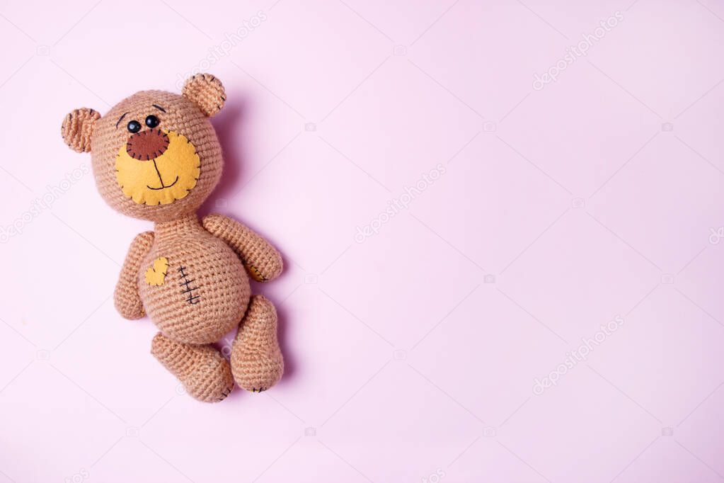 Toy teddy bear isolated on a pink background. Baby background. Copy space, top view.