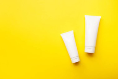 Parlak sarı arka planda krema şişeleri, üst manzara, kopyalama alanı. Kozmetik ürünleri ve cilt bakım konsepti. Model.