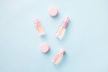 Çiçeklerin ve kozmetik ürünlerinin düzlüğü temel yağ: toner, serum, özü, nemlendirici ve mavi arka plan, üst görünüm, afiş. Yüz bakımı güzelliği