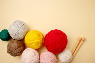 Beyaz ve kahverengi örgü yünü ve pastel arka planda örgü iğneleri. Üst görünüm, düz görünüm, kopyalama alanı.