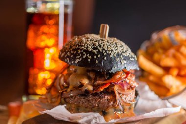 Kola ve patates kızartması arka planda siyah Cuma için siyah burger. Arka plan olarak koyu ahşap masa