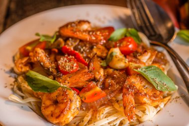 Deniz mahsulleri spagetti beyaz tabakta. Arka plan olarak koyu ahşap masa.