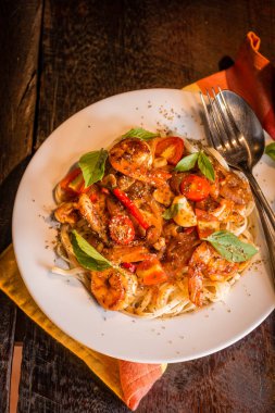 Deniz mahsulleri spagetti beyaz tabakta. Arka plan olarak koyu ahşap masa.