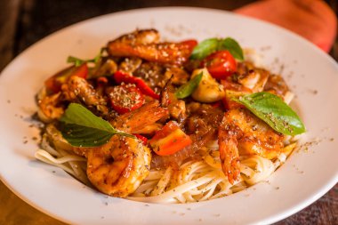 Deniz mahsulleri spagetti beyaz tabakta. Arka plan olarak koyu ahşap masa.