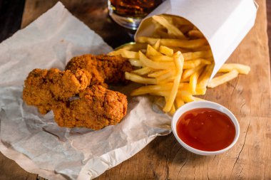 Baharatlı kızarmış tavuk bacak patates kızartması ve kola cam arka planda içmek