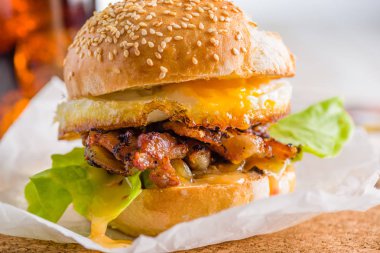 Beyaz arka plan üzerinde kızarmış yumurta burger Close-up. Kola ve gazete arka planda.