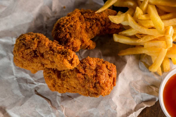 Spicy fried chicken leg potatoes fries and glass of cola drink in background