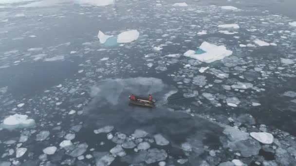 Лодка Зодиак отплывает на айсберг, отслеживая вид сверху — стоковое видео