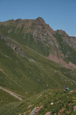 Sırt çantalı kadın turist kanyonun kenarında oturuyor.