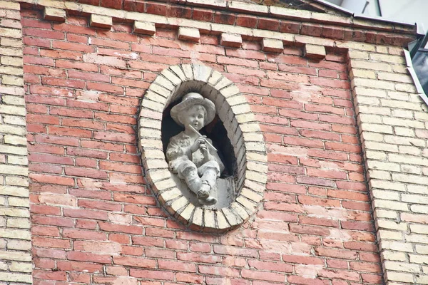 Estátua de um menino com um tubo na fachada — Fotografia de Stock