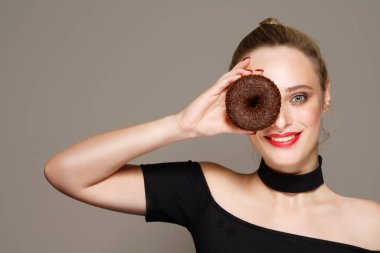 beauty portrait of attractive young caucasian woman blond on grey background studio shot looking at camera happy cheerful smiling theeth thoothy smile makeup red lips chocolate donut clipart
